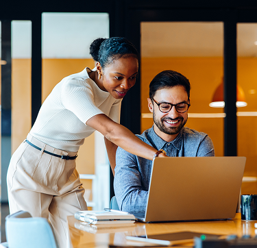 dos profesionales colaborando frente a una laptop en una oficina moderna