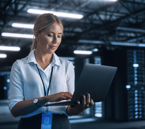 profesional revisando una laptop mientras camina por un centro de datos