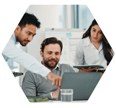 tres especialistas colaborando frente a un portátil en una oficina luminosa