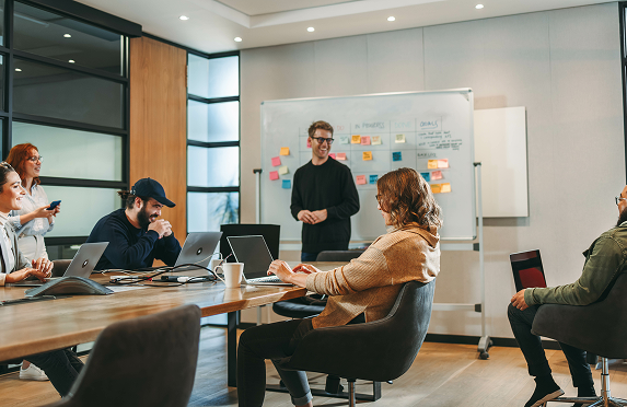 Tres profesionales sentados alrededor de una mesa de oficina con portátiles durante una reunión
