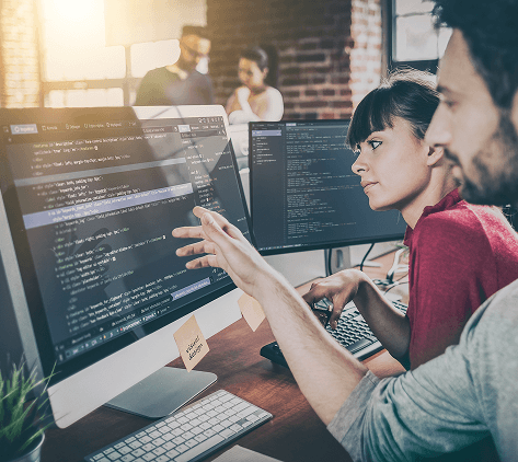 dos personas analizando y señalando código en una pantalla grande