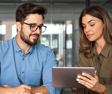 dos profesionales colaborando y revisando información en una tablet en una oficina