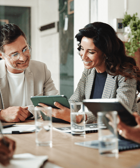 dos profesionales sonrientes revisando contenido en una tablet