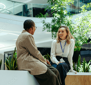 dos mujeres profesionales manteniendo una conversación en un espacio de oficina abierto