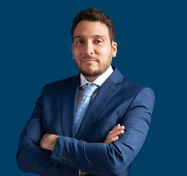 retrato de un hombre profesional con traje azul y brazos cruzados sobre un fondo oscuro